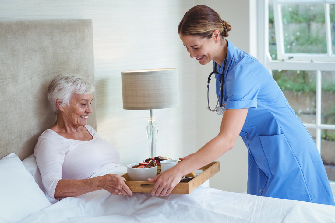 a nurse is handing a bowl of food to a woman in bed